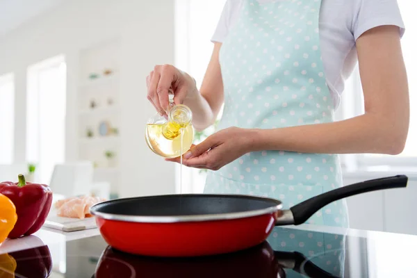 Cropped closeup photo of housewife hands holding olive oil bottle pouring warm frying pan weekend cooking tasty dinner preparation white light kitchen indoors — 스톡 사진