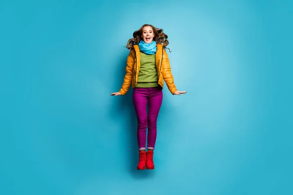Foto de tamaño completo de la señora bastante divertida saltar alto regocijo buen humor desgaste casual abrigo amarillo bufanda pantalones violeta botas rojas jersey verde aislado color azul fondo — Foto de Stock