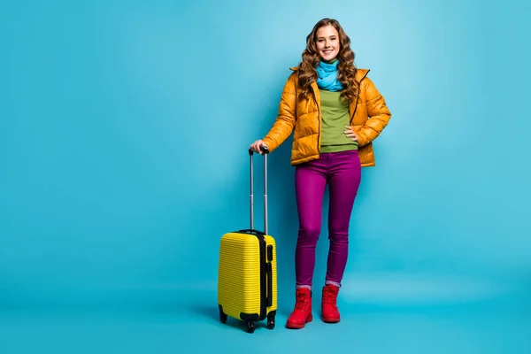 Volledige foto van vrij golvende dame reiziger houden rollende koffer wachten luchthaven vlucht registratie dragen gele overjas blauwe sjaal broek schoenen geïsoleerde blauwe kleur achtergrond — Stockfoto