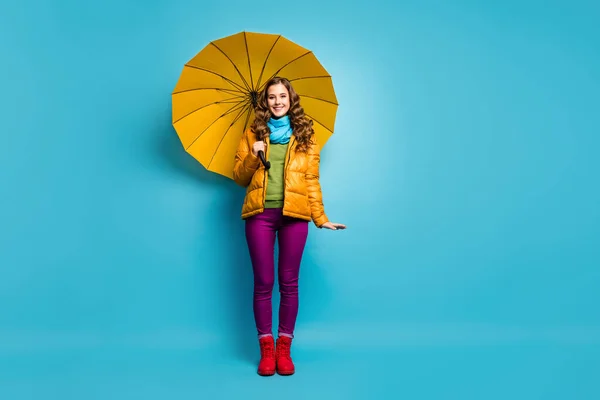Full body photo of funny pretty lady hold bright umbrella enjoy spring sunny day walk street abroad wear yellow overcoat scarf violet trousers red shoes isolated blue color background — Stock Photo, Image