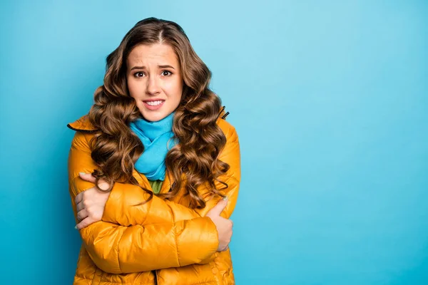Photo of pretty curly traveler lady upset frosty winter day shaking all body walk street hug herself wear trendy casual yellow overcoat blue scarf isolated blue color background — 스톡 사진