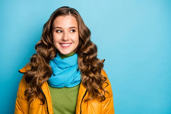 Photo of nice curly lady looking side empty space sunny winter day street look wear casual yellow warm overcoat blue scarf green pullover isolated blue color background — 스톡 사진