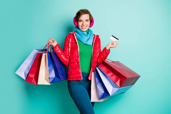 Θετική χαρούμενη γυναίκα ψώνια εθισμένος funky hipster αγοράζουν κρατήσει πολλές τσάντες πληρώνουν με debite κάρτα φορούν κόκκινο ροζ εξωτερικά ενδύματα πράσινο πουλόβερ μπλε παντελόνι παντελόνι απομονωμένο τυρκουάζ χρώμα φόντο — Φωτογραφία Αρχείου