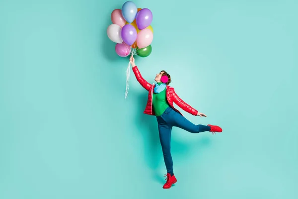 Volledige lengte profiel zijkant foto van vrolijk positief meisje genieten herfst vakantie vangen wind vliegen veel helium ballonnen dragen roze groene trui schoenen geïsoleerd over teal kleur achtergrond — Stockfoto