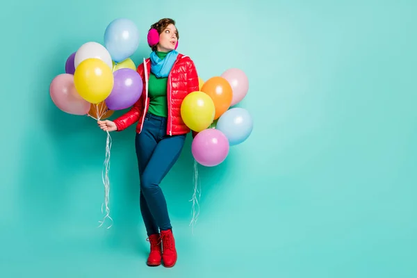 Foto de tamaño completo de la señora divertida sostienen muchos globos de aire coloridos estudiantes aspecto del partido espacio vacío desgaste casual abrigo rojo bufanda rosa oreja cubre pantalones zapatos aislados color verde azulado fondo — Foto de Stock