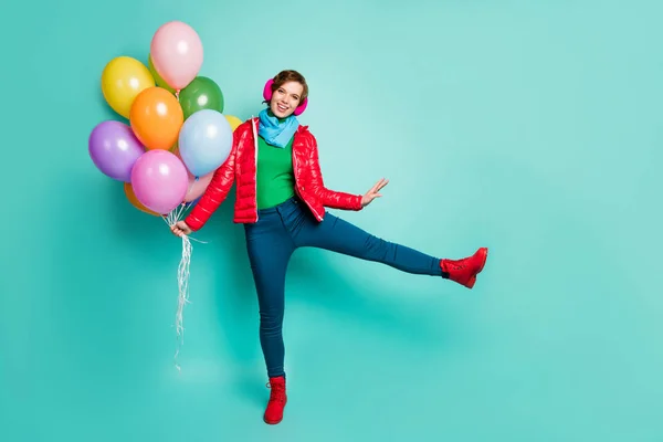 Фотографія повного розміру смішної енергійної леді приносить багато барвистих повітряних кульок студентам вечірки в повсякденному червоному пальто шарф рожеві вушні муфти штани взуття ізольовані сльозогінний колір фону — стокове фото