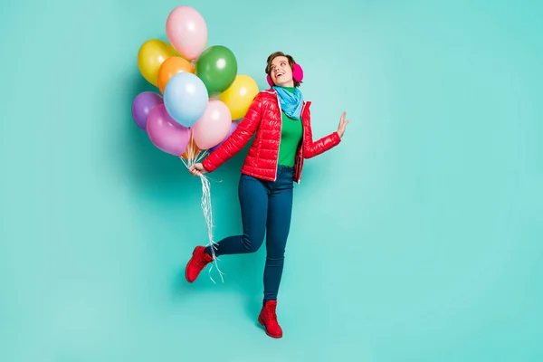 Full body photo of funny chilling lady came birthday party bring many colorful air balloons wear casual red coat scarf pink ear muffs pants shoes isolated teal color background