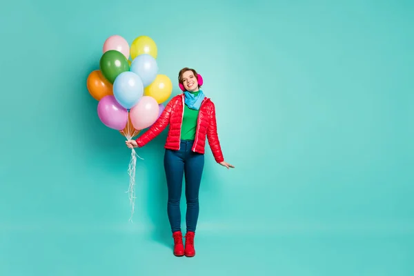 Full body photo of funny emotional lady came to birthday party bring many colorful air balloons wear casual red coat scarf pink ear muffs pants shoes isolated teal color background