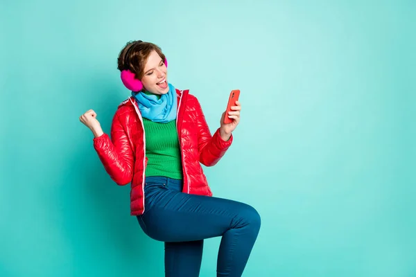 Фото красивой леди держать телефон руку празднуя хорошие комментарии новый блог люди реакция носить красное пальто шарф розовый ухо крышки свитера брюки изолированные бирюзовый цвет фона — стоковое фото