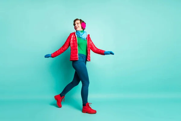 Foto de perfil de comprimento total de senhora engraçada desfrutar de dia de inverno passar o tempo ativo andar rua desgaste casual vermelho sobretudo azul cachecol rosa orelha aquecedores calças isolado teal cor fundo — Fotografia de Stock