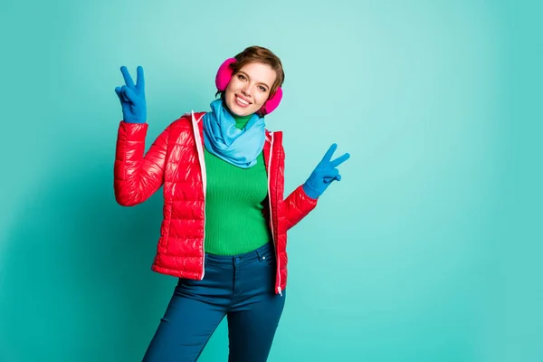 Φωτογραφία από αστείο ταξιδιώτη κυρία απολαύσετε ηλιόλουστη ημέρα του χειμώνα χαρά δείχνει σύμβολο v-σημάδι πατινάζ φορούν casual κόκκινο πανωφόρι μπλε κασκόλ ροζ καλύμματα αυτιών παντελόνι απομονωμένο φόντο teal χρώμα — Φωτογραφία Αρχείου