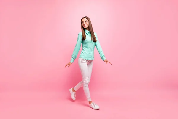 Full body foto van grappige mooie dame lopen naar beneden straat genieten van zonnige dag weer dragen specs turquoise shirt witte broek geïsoleerde roze kleur achtergrond — Stockfoto