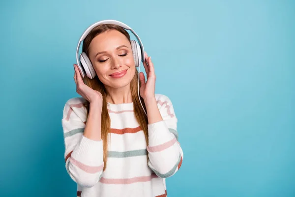 Foto av glad kvinna med stängda ögon charmig ganska söt i hörlurar lyssna på musik nära tomt utrymme isolerad pastell färg bakgrund — Stockfoto