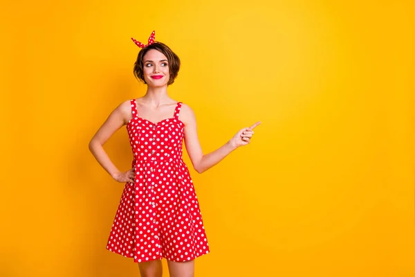 Porträtt av positiva glada flicka promotor peka pekfinger copyspace visar annonser marknadsföring bära sommar röd stil kjol isolerad över glans färg bakgrund — Stockfoto
