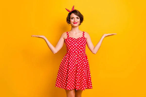 Portrait of positive cheerful girl hold hand display ads promotion recommend suggest select offer object wear red polka-dot skirt isolated over shine color background — 스톡 사진