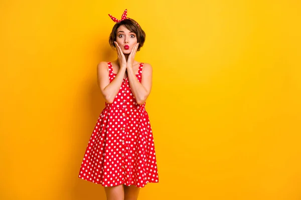 Фото смішної красивої леді тримає руки на щоках, що відправляють повітряний поцілунок, кокетливий настрій, одягнений в ретро літнє плямисте червоне біле плаття на голові, ізольований яскраво-жовтий кольоровий фон — стокове фото