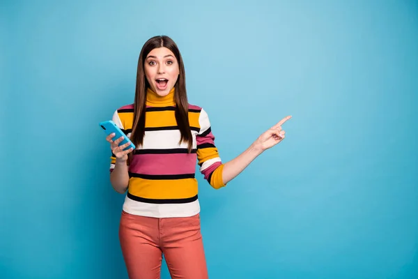 Удивительно сумасшедшая девушка указатель пальца копировать пространство использования смартфона показывают невероятную рекламу впечатляет крик Омг носить красные брюки свитер изолированный синий цвет фона — стоковое фото