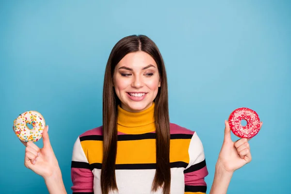 Close up photo of content girl hold two doughnuts look want eat yummy fast food wear modern colorful outfit isolated over blue color background — ストック写真