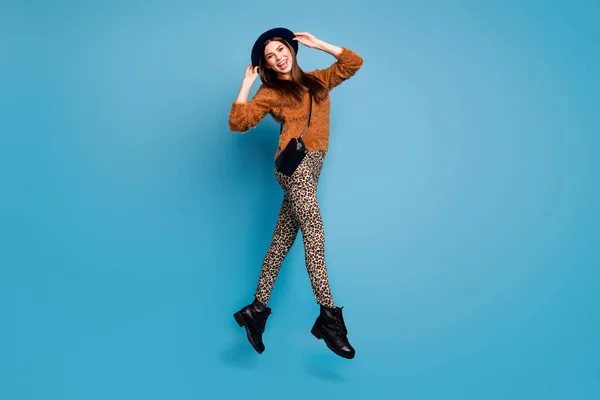 Full length photo of charming cute girl jump touch her retro style hat enjoy emotions wear casual clothing clutch black boots isolated over blue color background — ストック写真