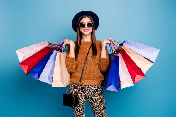 Portrait of cheerful funky girl tourist enjoy shopping weekends buy off-sales hold many bags wear velvet vintage hat clutch brown trousers pullover sunglass isolated blue color background — 스톡 사진