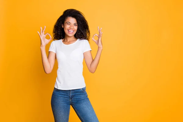 Photo of positive cheerful nice cute pretty sweet girl in jeans denim white t-shirt showing double ok sign smiling toothily winking near empty space isolated vivid color background — Stock Photo, Image