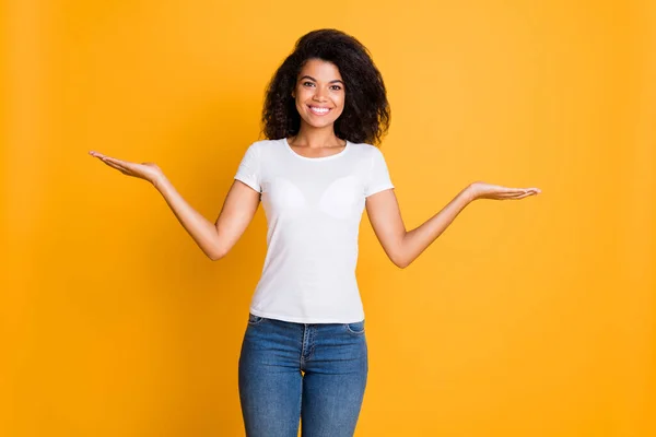 Фото веселой позитивной милой милой милой девушки в джинсах в белой футболке с двумя объектами на руках, улыбающимися зубами, показывающими изолированный яркий цвет фона — стоковое фото