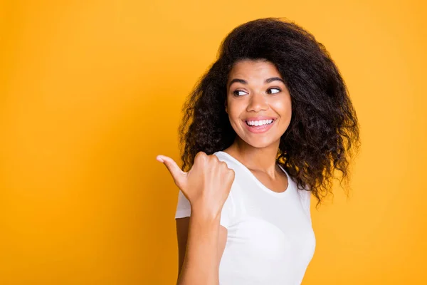 Foto van vrolijke positieve mooie vriendin wijzen naar lege ruimte met duim glimlachend getand in wit t-shirt geïsoleerde levendige kleur achtergrond — Stockfoto