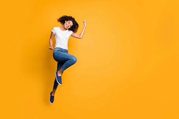 Tamanho total do corpo foto de alegre positivo encaracolado ondulado agradável encantador menina regozijando-se sobre sua equipe ganhar as competições vestindo jeans jeans branco t-shirt isolado cor viva fundo — Fotografia de Stock