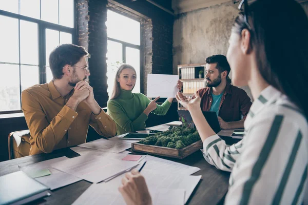 Firmaet består av fire attraktive faglærte meglere som sitter rundt bordet og diskuterer avtale på arbeidsplassens kontor – stockfoto
