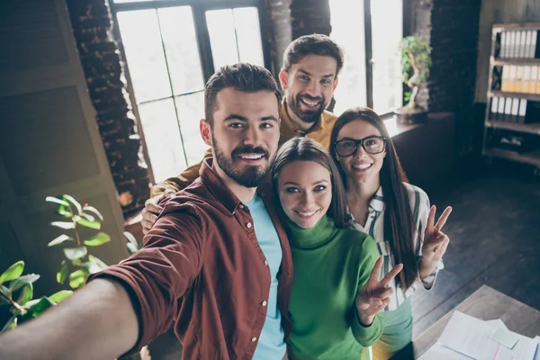 Self-portrait of four nice attractive friendly cheerful cheery professional businesspeople agents brokers showing v-sign having fun at industrial loft interior style workplace workstation office — ストック写真