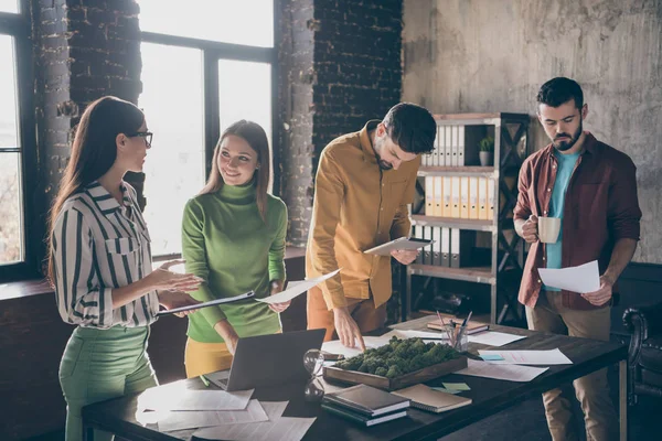 Kompani med fire hyggelige, smarte, muntre medarbeidere som utarbeider rapportstrategi på arbeidsplassen – stockfoto