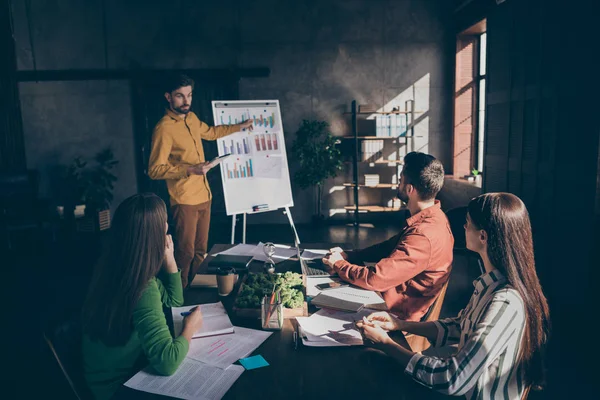 Foto av seriøse forretningsfolk som har seminar på moderne teknologi om å være entreprenører med mennesket stående nær figurer som viser økt inntekt – stockfoto