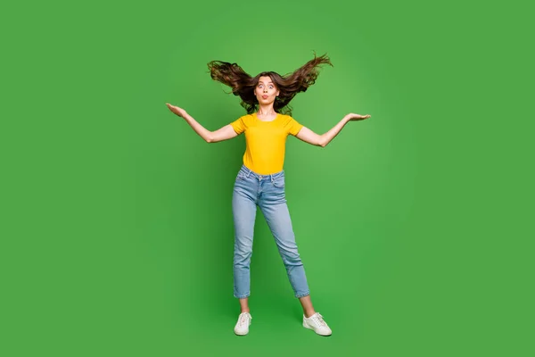 Full length photo of pretty funny lady sending air kisses making crazy facial expression throwing hair up wear casual yellow t-shirt jeans isolated bright green color background — Stok fotoğraf