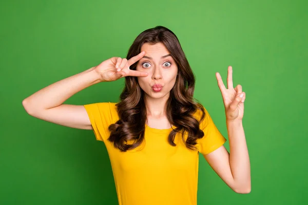 Foto de señora joven divertida mostrando símbolos v-signo ambos brazos enviando besos de aire chico guapo humor coqueto desgaste casual camiseta amarilla aislado color verde brillante fondo —  Fotos de Stock