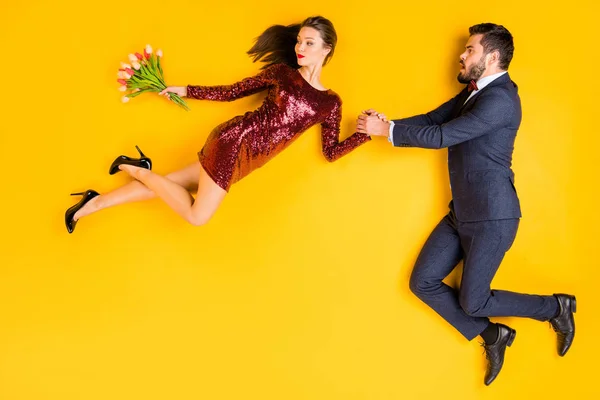 Top powyżej wysoki kąt profil strona pełne ciało zdjęcie dwóch osób data boi się mężczyzna trzymać rękę złapać sprytny kobieta latać wiatr nosić tulipany kilka nosić smokingi sukienka leżał odizolowany żółty kolor tło — Zdjęcie stockowe