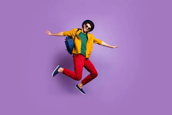 Ganzkörperfoto von fröhlichen Kerl springen halten Hände wie Flugzeug genießen Ruhe entspannen tragen gelb modern Hemd blau Samt Retro-Kopfbedeckung isoliert über violetten Farbhintergrund — Stockfoto