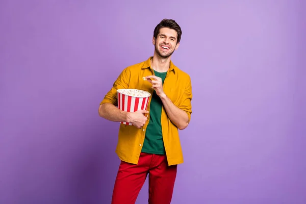 Portrait of positive cheerful guy have free time hold big pop corn box watch tv funny series laugh wear youth modern clothes isolated over violet color background — 스톡 사진