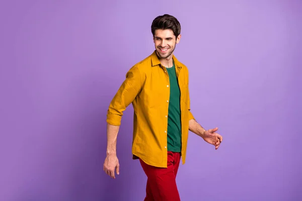 Foto von selbstbewussten, fröhlichen Mann, der vorwärts geht und rückblickend in grünem T-Shirt zurückblickt, isoliert violett pastellfarbenen Hintergrund — Stockfoto