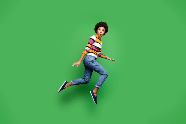 フルサイズプロフィール側の写真の負パニックアフロアメリカのヒップスター女の子見てコピースペースモンスタージャンプ実行着用秋デニムジーンズ明るい隔離された緑の色の背景 — ストック写真