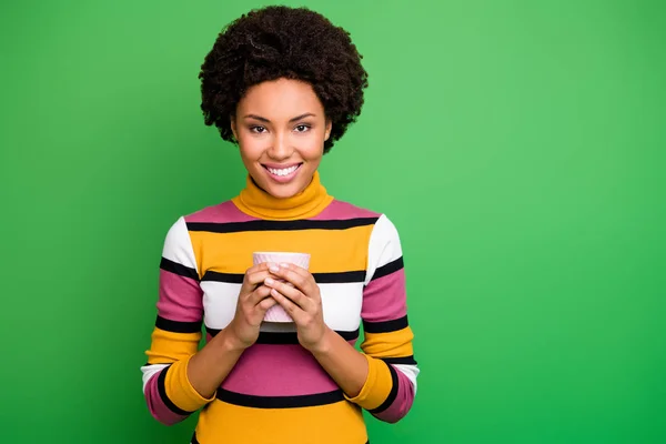 Ritratto di allegra calma afro americana ragazza tenere caldo caffeina bevanda tazza godere di autunno fine settimana indossare abiti buon look isolato su sfondo di colore verde — Foto Stock
