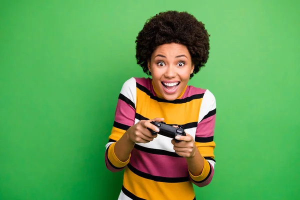 Foto van grappige donkere huid dame goed humeur spelen video games verslaafde gamer enthousiast houden joystick handen dragen casual gestreepte trui geïsoleerde groene kleur achtergrond — Stockfoto