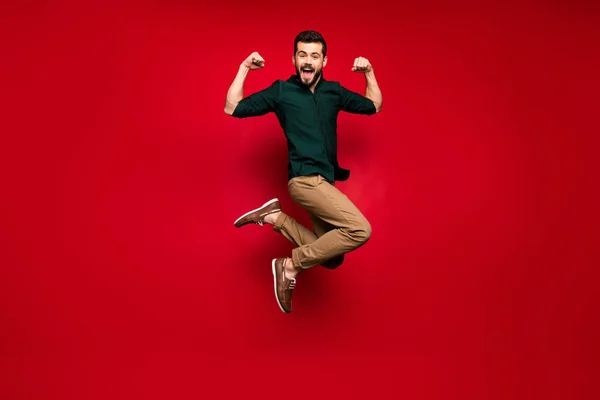 Full body photo of cheerful guy jump show his power musclar hands triceps win sport contest scream feel crazy expression wear green brown shirt sneakers isolated shine color background — Stockfoto