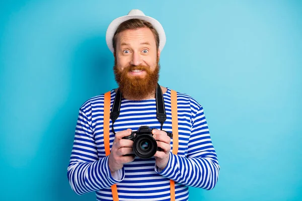 Retrato de homem alegre positivo viajante segurar câmera digital dslr desfrutar de férias desgaste branco colete náutico headwear isolado sobre fundo de cor azul — Fotografia de Stock