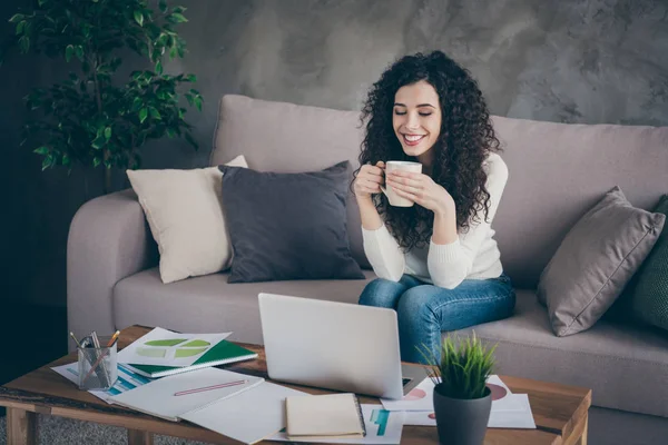 Portrait of her she nice attractive lovely cheerful wavy-haired girl sitting on divan drinking coffee watching video online in modern loft industrial style interior living-room indoors — Stock Photo, Image