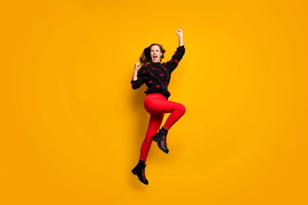 Photo de profil pleine longueur de dame drôle sautant haut réjouissant levant poings sauvage fan de football porter coeur motif pull pantalon rouge chaussures isolé fond de couleur jaune — Photo