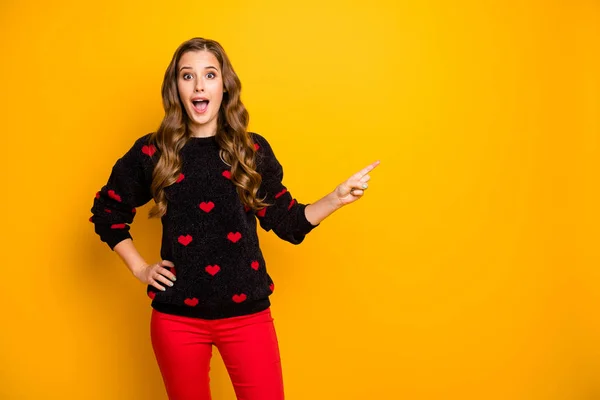 Photo of funny shocked lady open mouth wskazując palcem pustej przestrzeni doradzając niskie ceny sezonu handlowego nosić serca wzór pullover czerwone spodnie odizolowane żółty kolor tło — Zdjęcie stockowe