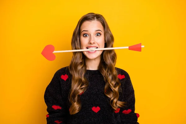 Photo of funny crazy lady work as cupid hold arrow in mouth ready to give people couples love feelings wear hearts pattern pullover isolated yellow color background — 스톡 사진