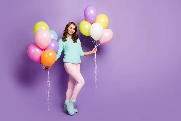 Foto de longitud completa de la señora bastante divertida traer muchos globos de aire coloridos amigos evento cumpleaños fiesta desgaste difusa suéter rosa pantalones pastel botas aisladas color púrpura fondo — Foto de Stock