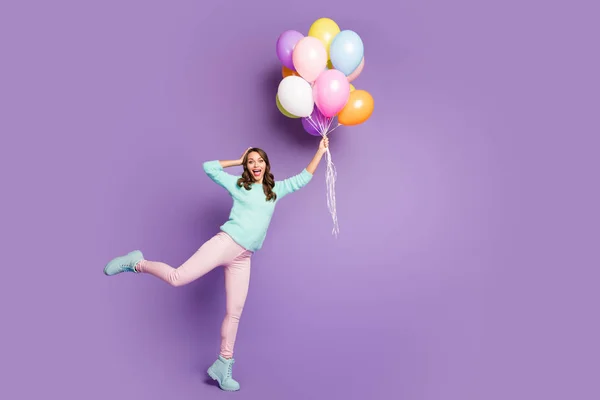 Full storlek foto av överraskad feminin flicka få närvarande många baloons flygande himmel hon fånga imponerad skrik wow omg bära rosa byxor pastell turkos tröja isolerad lila färg bakgrund — Stockfoto