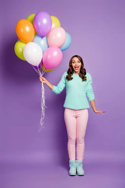 Πλήρης σώμα κάθετη φωτογραφία της όμορφης κυρίας φέρει πολλά πολύχρωμα μπαλόνια αέρα φίλους εκδήλωση κόμμα φορούν χνουδωτή μέντα πουλόβερ ροζ παστέλ παντελόνι παπούτσια απομονωμένο πορφυρό χρώμα φόντο — Φωτογραφία Αρχείου